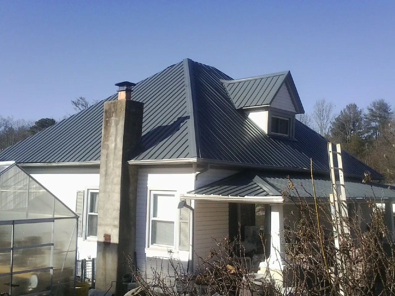 Dark blue standing seam metal roof on a white farmhouse with dormer — Slate & Tile Roof Repair by Roofing Brothers in Bergenfield