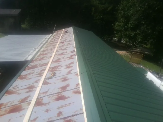 Old rusted panels beside newly installed green metal roofing — Wind Damage Roof Repair by Roofing Brothers in Bergenfield
