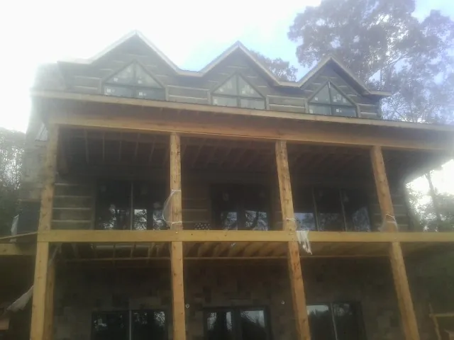 Dormers and porch framing on a large log home under construction — Roof Coating work by our crew in Bergenfield