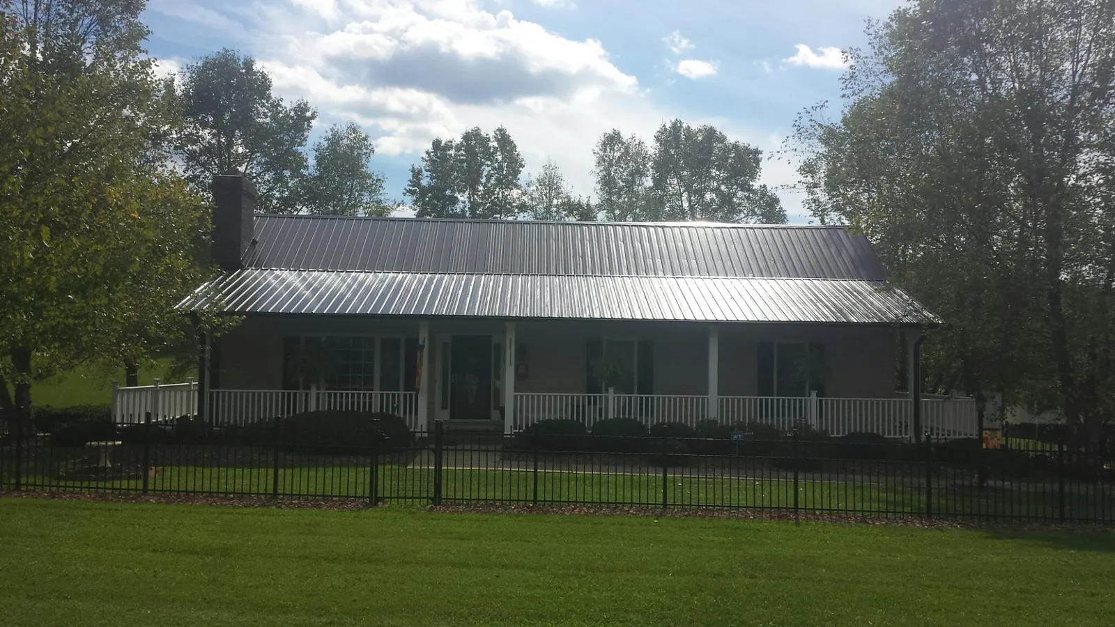 Gray metal roof on a brick ranch with a full width front porch — Gutter Guard Installation work by our crew in Bergenfield
