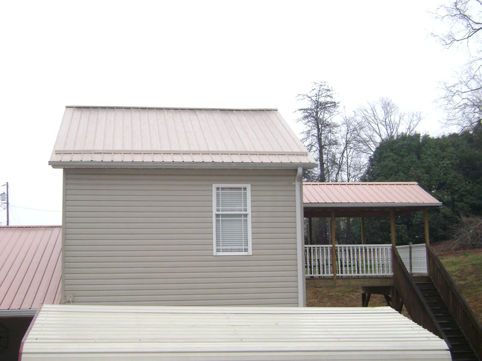 Tan metal roofs on a two story addition and attached porch, from a Roof Replacement job in Bergenfield