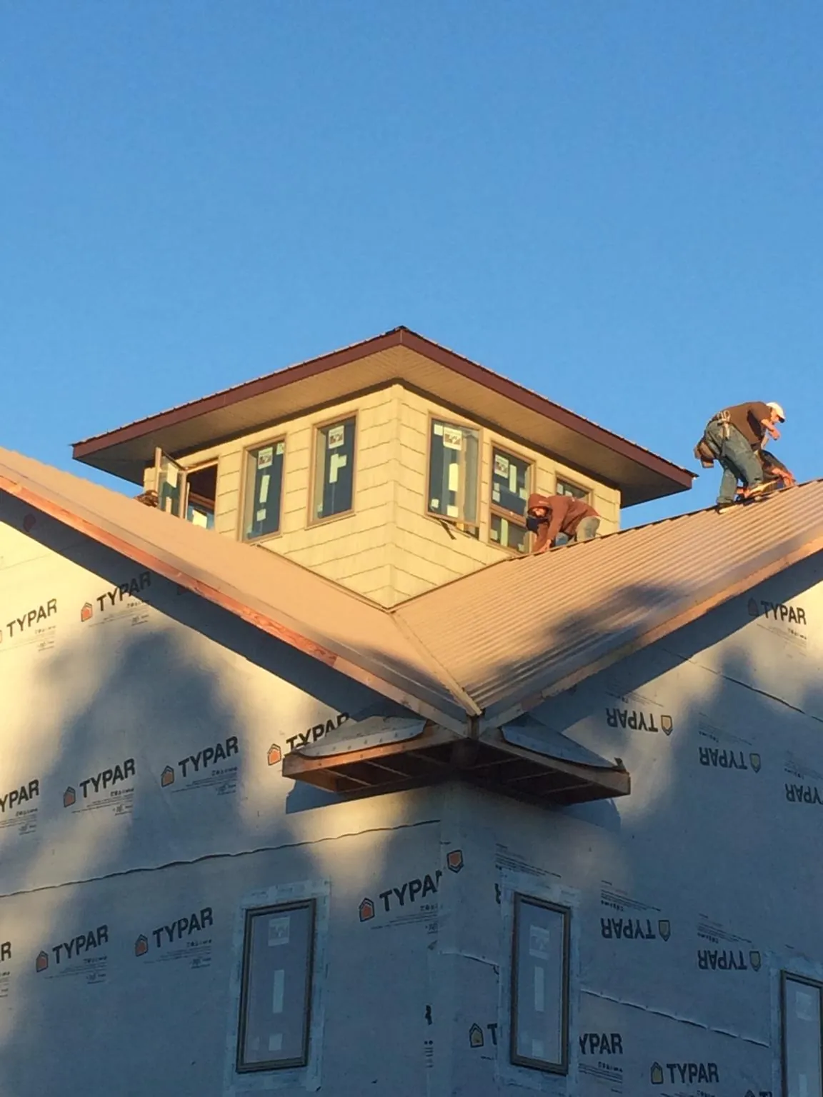 Roofers working around a rooftop cupola on a new metal roof at sunset — Roof Waterproofing in Bergenfield by Roofing Brothers